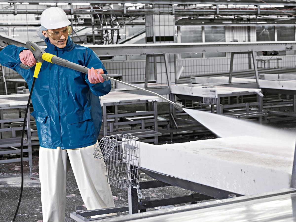 Man using a Pressure Washer to clean inside a factory