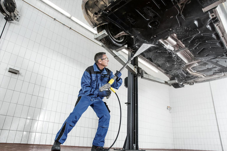 Cleaning the bottom of a car in a garage with a Cold Pressure Washer